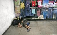 Homeless boys sleep in front of a children's clothing store in the capital.