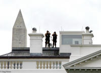 Security detail and Washington Monument loom above the White House.