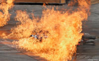 A motorcycle stuntman slides through flames on a Hollywood movie set.